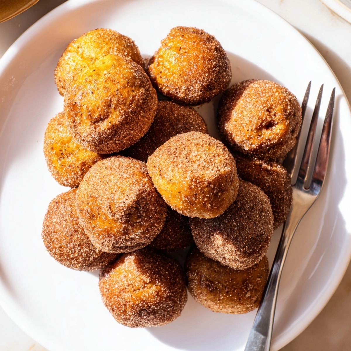 Golden Bite-Size Pumpkin Muffin Balls warm from the oven, coated in cinnamon sugar.