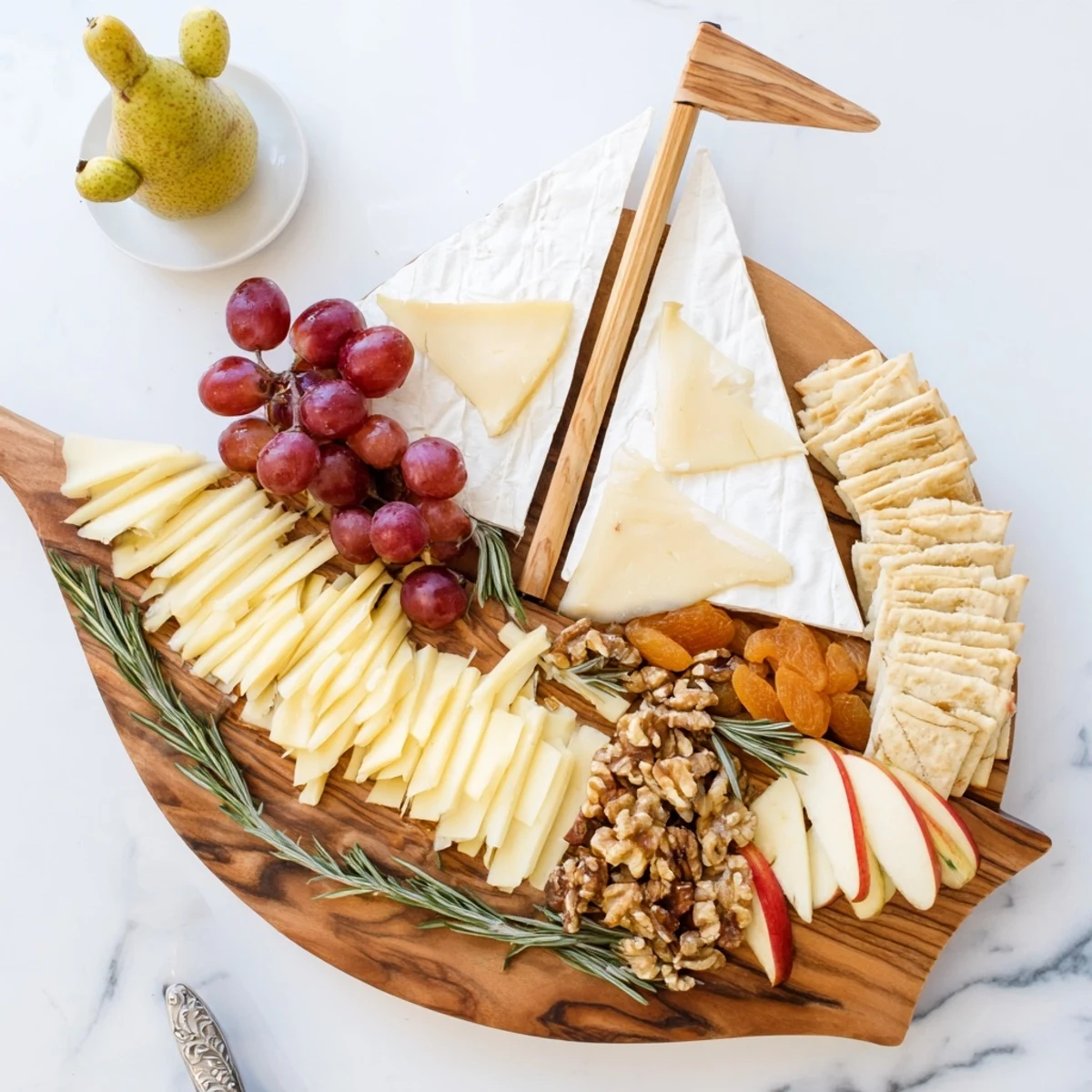 Sailboat cheese platter featuring an assortment of cheeses, fruits, and nuts, perfect for appetizers.