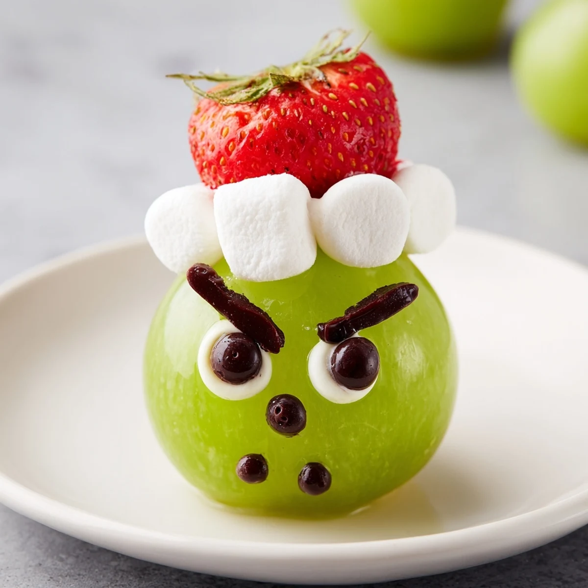 Vibrant Grinch Snack faces: a green grape base with marshmallow smiles are arranged here.