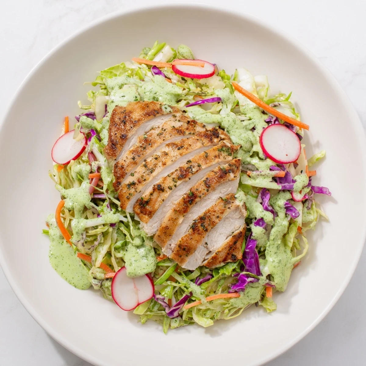 Green Goddess Cabbage Slaw with Grilled Chicken, a colorful, creamy slaw topped with grilled chicken slices.