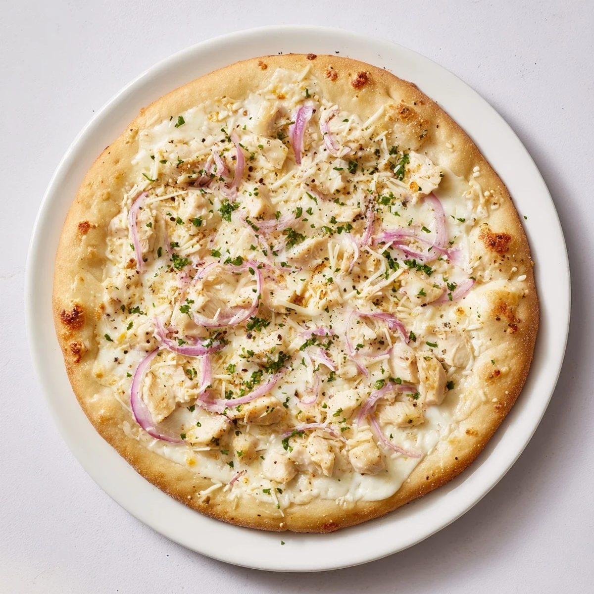 Delectable Chicken Alfredo Pizza, a generous slice featuring savory chicken, served on a white plate.
