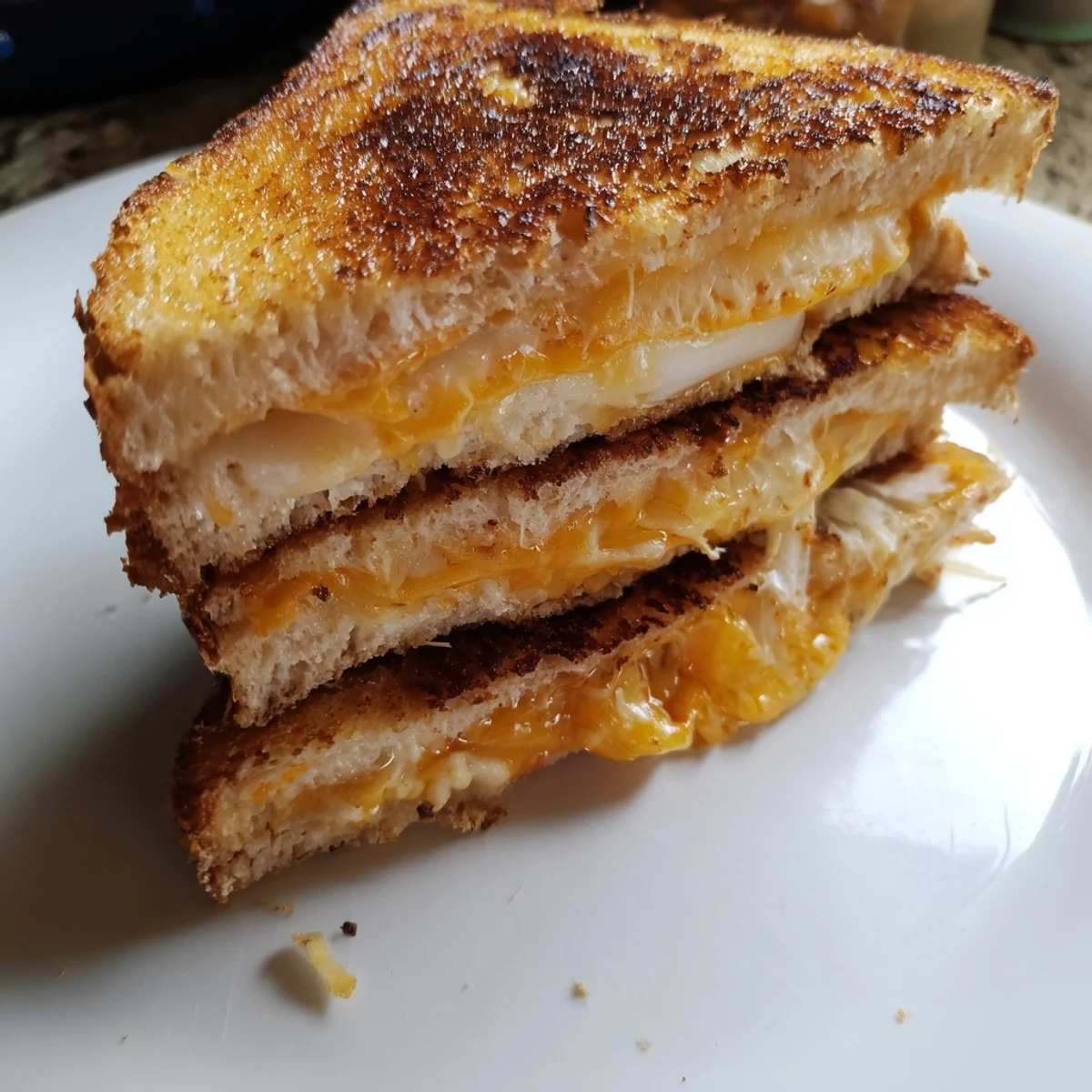 Crispy, bubbly Triple Cheese Sourdough Grilled Cheese ready to serve alongside a warm bowl of tomato soup.