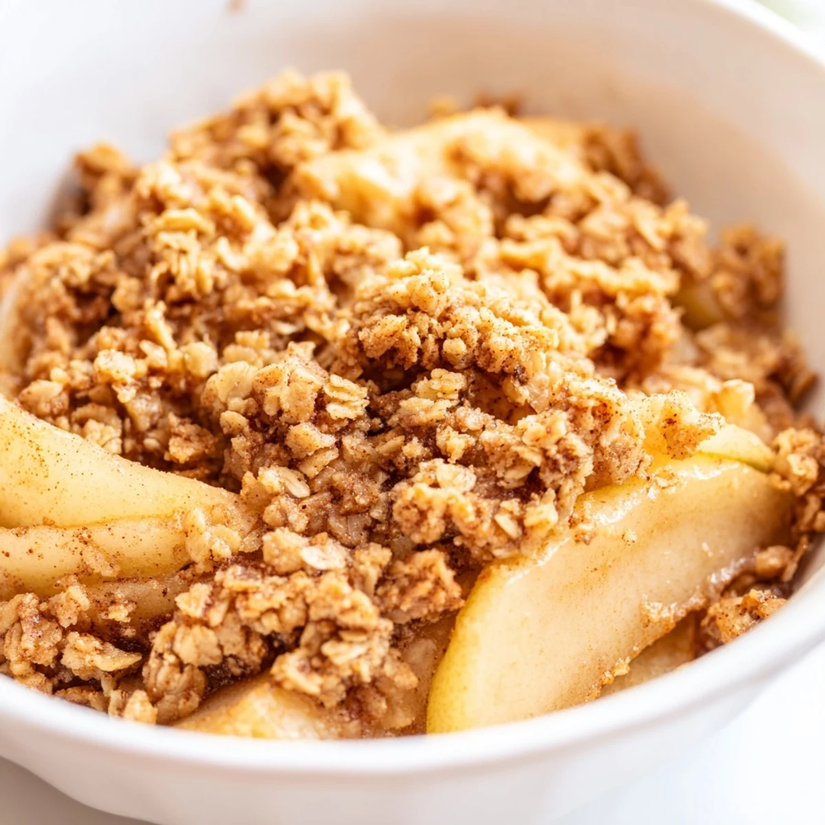 Freshly baked pear crumble showcases bubbling golden pears beneath a thick, crunchy oat topping, ready to enjoy.