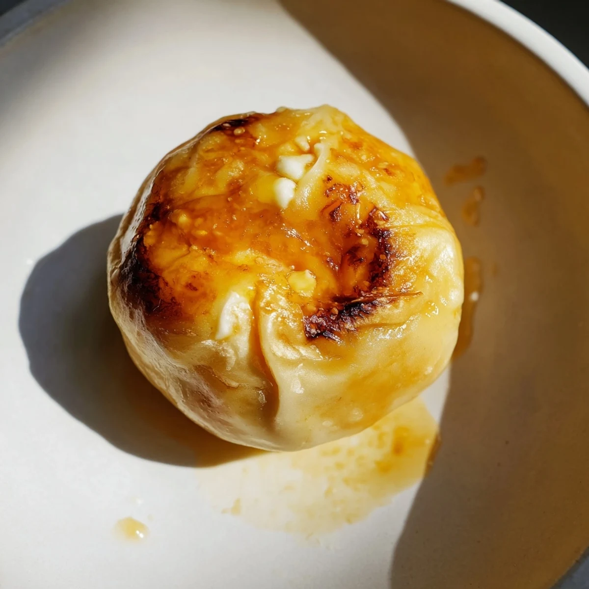 Freshly cooked Chīzu Imomochi, Japanese potato mochi with a golden crust and gooey mozzarella filling, glistening under a thick soy-honey glaze, sitting beside a bowl of mirin-based dipping sauce and sesame seeds.