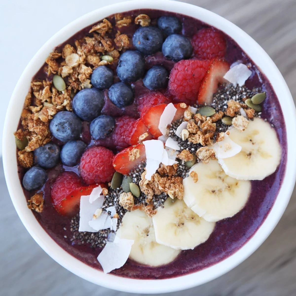 Thick, creamy Acai Berry Smoothie Bowl made with frozen acai and berries, adorned with chia seeds, coconut flakes, and sliced fruit.