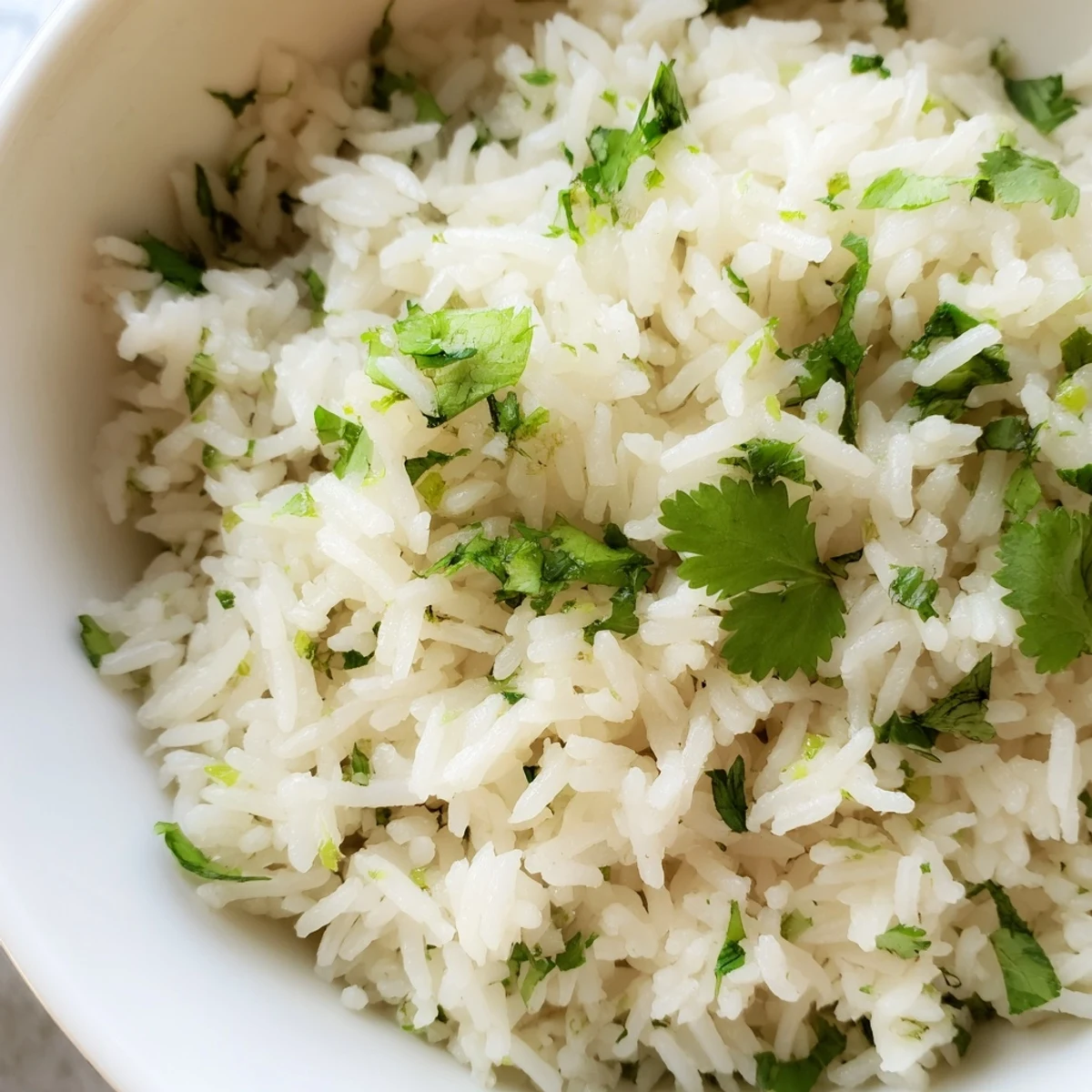 Fluffy Cilantro Lime Rice steamed to perfection, topped with fresh chopped cilantro and a zesty lime wedge on a rustic wooden table.