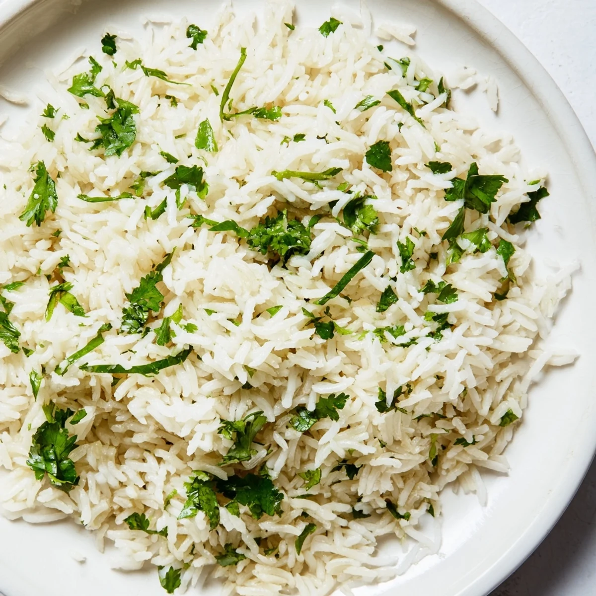 A bowl of aromatic Cilantro Lime Rice garnished with bright green herbs and a wedge of lime, ready to accompany your favorite tacos.