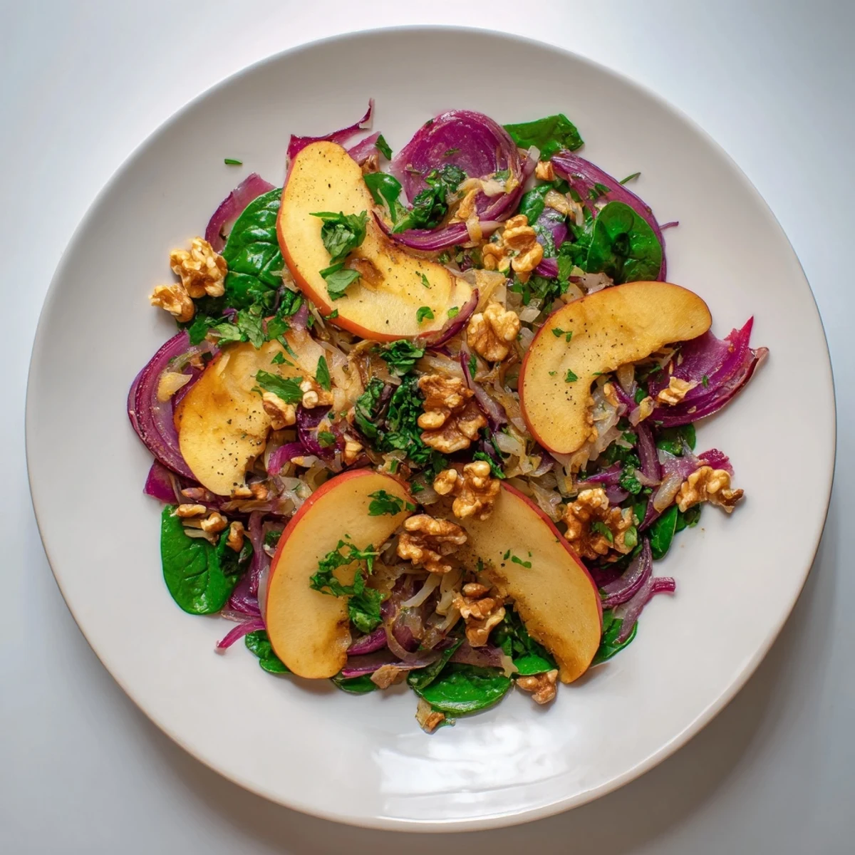 Overhead view of Warm Apple and Sauerkraut Skillet Salad served on a rustic platter with spinach and toasted walnuts, perfect for a healthy weeknight meal.