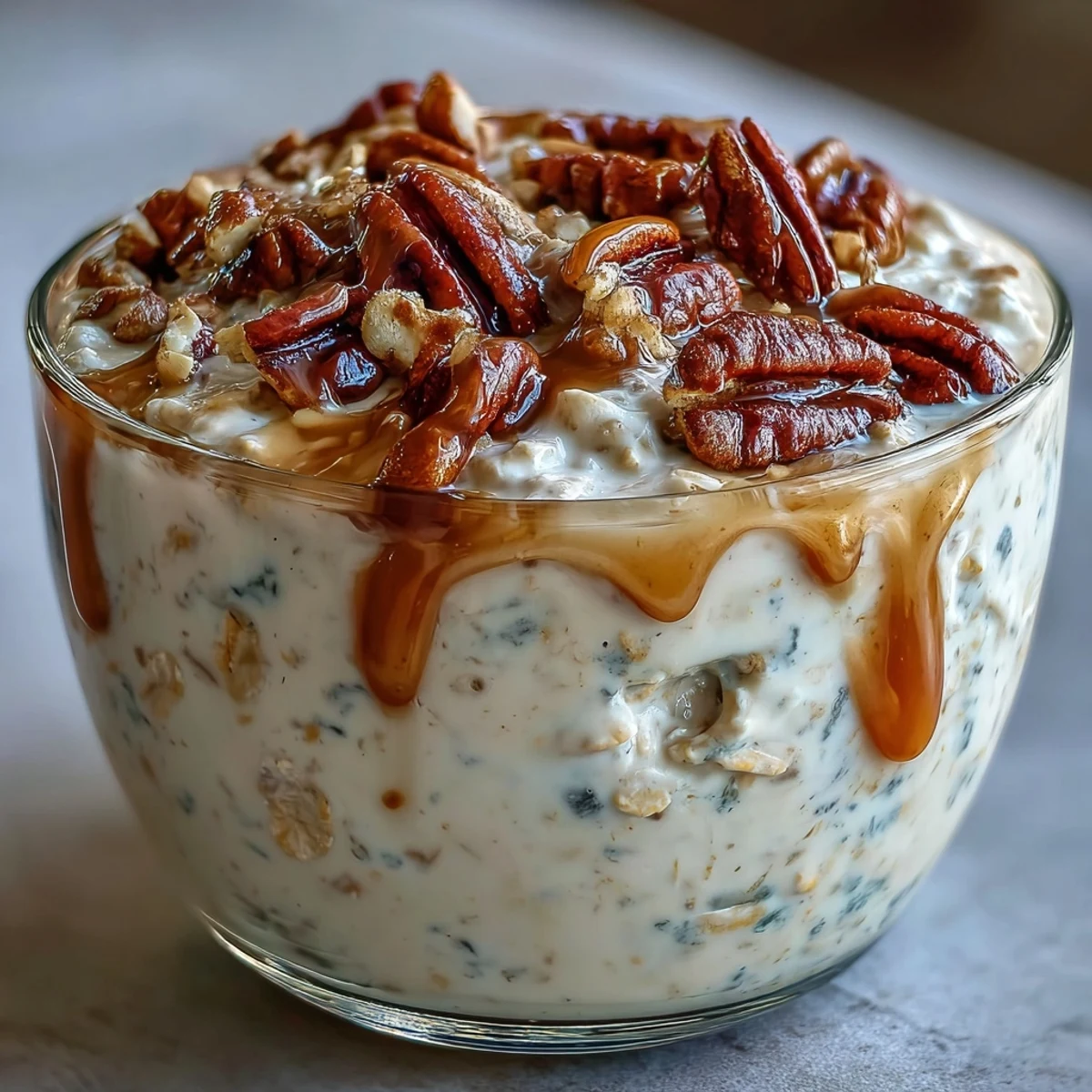 Creamy overnight oats with crunchy candied pecans and a maple syrup drizzle in a glass jar.  