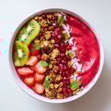 This photo features creamy Festive Red and Green Smoothie Bowls, overflowing with fresh fruit toppings and coconut flakes.
