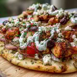 A golden, crispy-edged naan crust loaded with seasoned chicken, creamy feta, and thin red onion slices, finished with a drizzle.