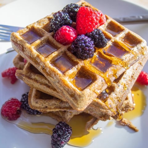 Golden Cinnamon Vanilla Oat Waffles, crispy and steaming, drizzled with maple syrup and berries