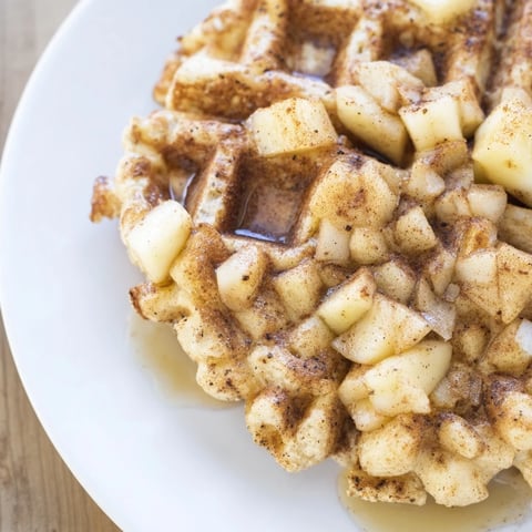 Fluffy Cinnamon Apple Protein Waffles stacked high, drizzled with maple syrup for breakfast bliss.  
