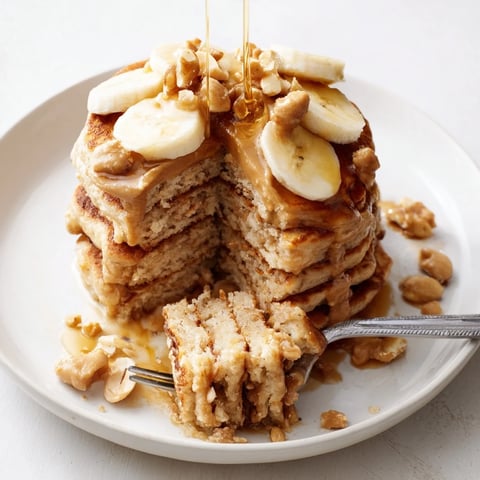 Fluffy Peanut Butter Maple Oat Pancakes topped with sliced bananas and warm syrup.  