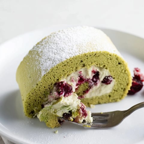 Light and airy Matcha Swiss Roll with tangy cranberry cream filling on a plate.