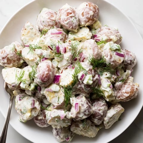 Creamy Spicy Pickle Ranch Potato Salad garnished with fresh herbs, perfect for summer picnics.  