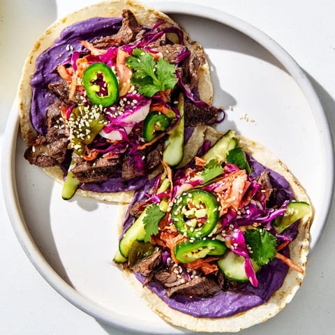 Vibrant Global Street-Food Fusion Tacos topped with ube crema and fresh vegetables.