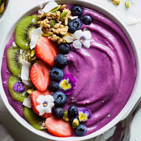 Vibrant smoothie bowls with purple yam and pistachio, topped with fresh fruit.  