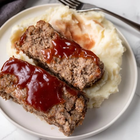 Juicy classic meatloaf with savory glaze and creamy mashed potatoes, perfect for family dining.  