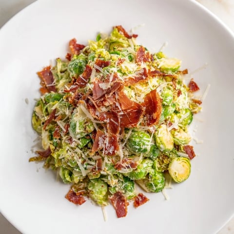 Warm Brussels Sprouts Caesar salad, featuring crispy prosciutto and shaved Parmesan, a delightful meal.