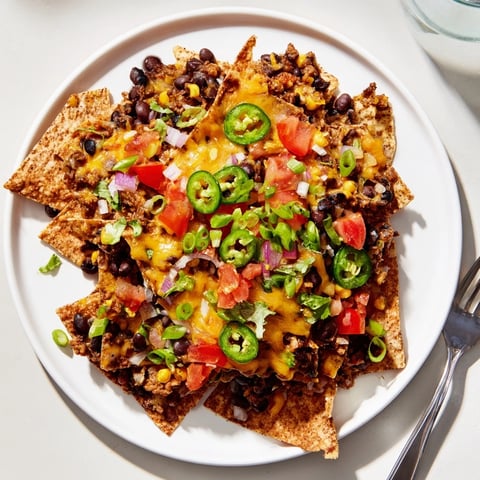 Sheet-Pan Nachos with Pantry Beans are bubbling and golden, cheese melted over colorful frozen veggies.