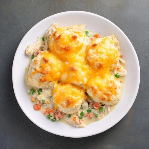 Golden brown cheddar biscuits topping bubbling one-pan chicken cobbler ready for serving.