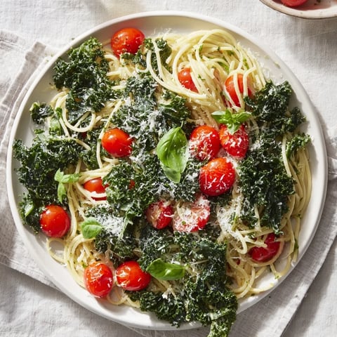 Steaming one-pot spaghetti with kale and tomatoes, topped with fresh basil, ready to serve and enjoy.