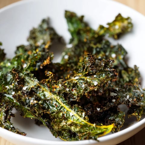 Golden, crispy Baked Kale Chips arranged perfectly on parchment paper, ready to eat.