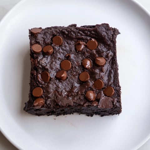 Fudgy Black Bean Brownies are shown, topped with chocolate chips; a perfect gluten-free dessert.
