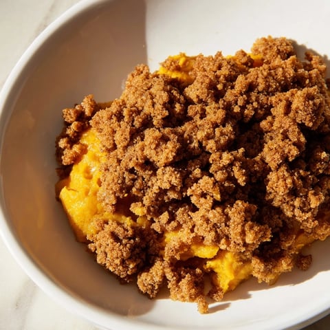 Golden-brown Pumpkin Crisp, a warm dessert with a bubbly pumpkin base under a sweet crumble.