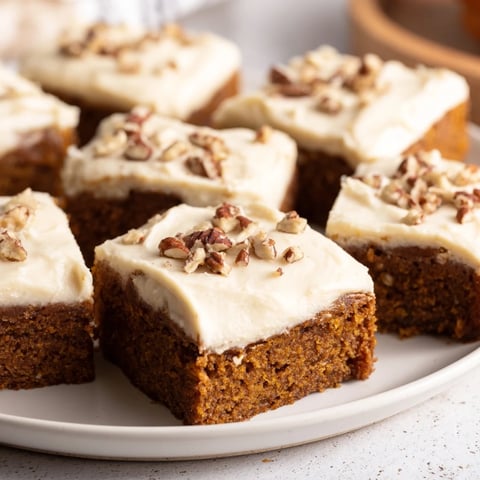 Golden-frosted pumpkin bars, a spiced autumn dessert, ready to slice and savor.