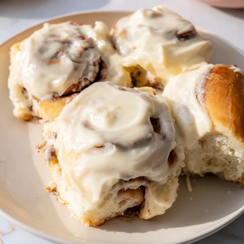 Fluffy Viral TikTok Heavy Cream Cinnamon Rolls baking in a dish, golden and glistening, ready to eat.
