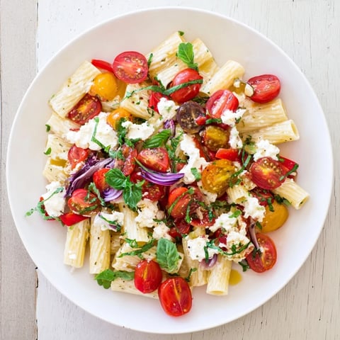 Golden baked feta nestled in one-pan baked feta Christmas pasta with vibrant, bursting cherry tomatoes.