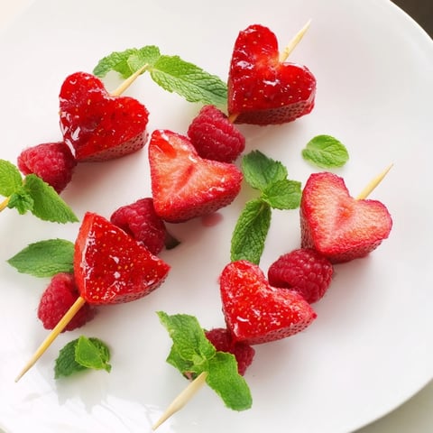 Red heart fruit skewers: vibrant dessert skewer arrangement with strawberries and watermelon hearts, ready to enjoy.