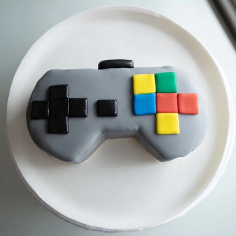 Vibrant pixel game controller cake, with fondant buttons, ready to delight any gamer’s birthday party.