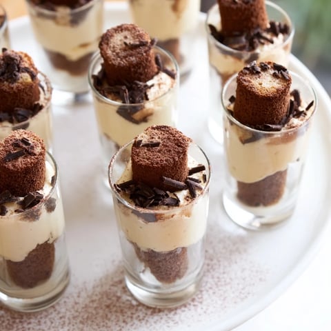Countdown Tiramisu Shots in mini glasses layered with creamy mascarpone, coffee-soaked ladyfingers, and cocoa.
