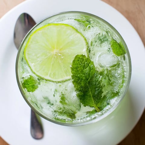 Refreshing Mint Lime Agua Fresca, garnished with lime, offers a burst of citrus flavor.