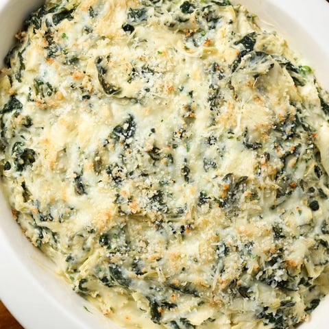 Warm and bubbling cheesy spinach artichoke dip, perfect for dipping tortilla chips at a party.