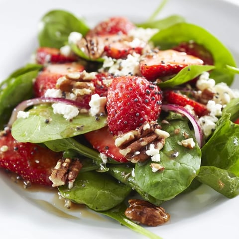 Fresh spinach strawberry salad bursting with color, topped with toasted pecans and feta cheese.