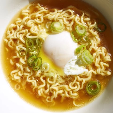 Steaming bowl of upgraded instant ramen with a perfectly cooked soft egg, ready to eat.
