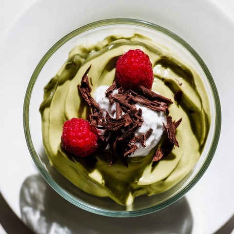 Creamy avocado chocolate pudding, swirled and topped with fresh berries, ready to eat.