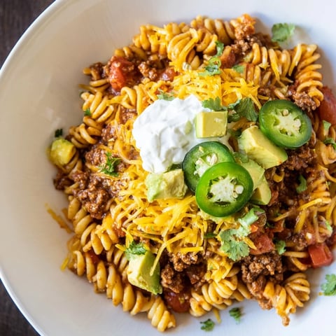 Beef Taco Pasta Skillet bubbling in a skillet, topped with melted cheddar, ready to serve with fresh cilantro.