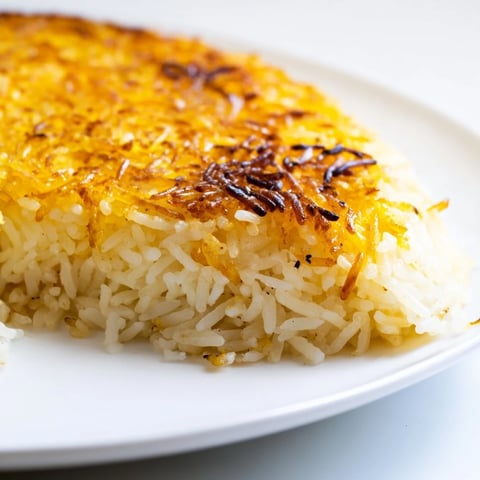 Golden and crispy Persian Tahdig rice with steam rising, a delicious and flavorful vegetarian side dish.