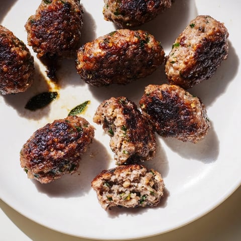 Golden-brown Turkish Köfte meatballs, pan-fried to perfection, are ready to serve with fresh herbs.