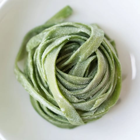 Fresh spinach pasta dough, vibrantly green, resting before being shaped for delicious meals.