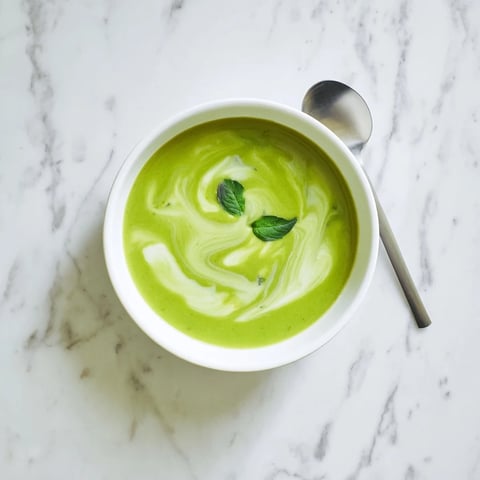 Bright green Courgette, Pea and Pesto Soup in a rustic bowl, swirled with extra pesto and fresh basil garnish for a vibrant spring lunch.
