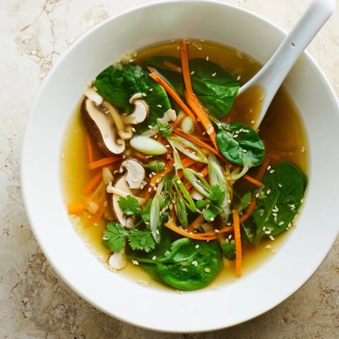 A warm bowl of Miso Ginger Winter Soup with julienned carrots, shiitake mushrooms, and wilted spinach.