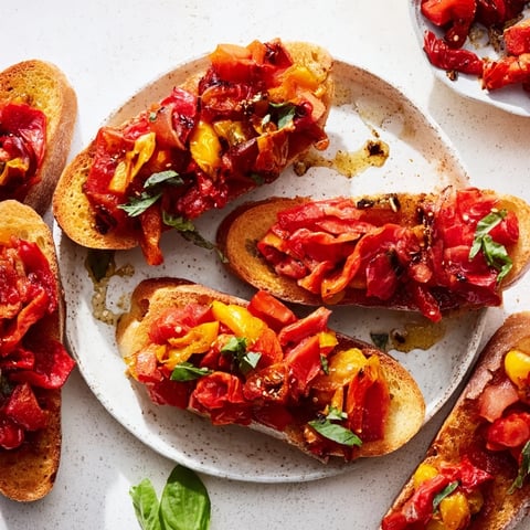 Vibrant fire-roasted tomato and pepper bruschetta served on crispy baguette slices.  