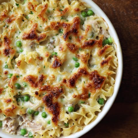 A bowl of food with noodles and peas.