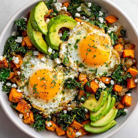 A bowl of food with eggs, avocado, and greens.